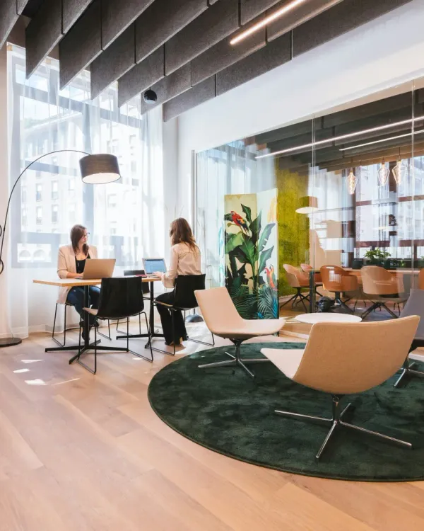Zwei Personen arbeiten gemeinsam an Laptops in einem modernen Büro