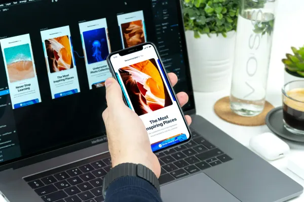 Smartphone mit App-Design vor einem Laptop